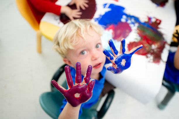 手沾满蓝色和紫色油漆的蹒跚学步的男孩图片下载