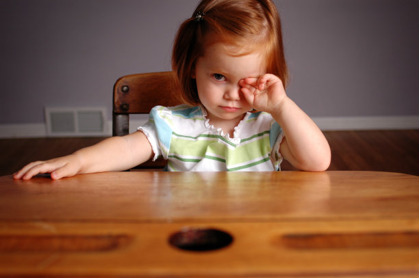 紧张的小女孩坐在课桌上素材图片