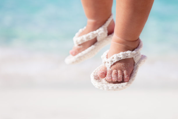 在加勒比海滩上穿着白色凉鞋的婴儿脚图片下载