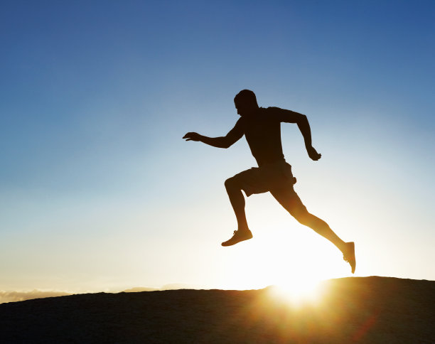 一个奔向夕阳的年轻人的剪影图片下载