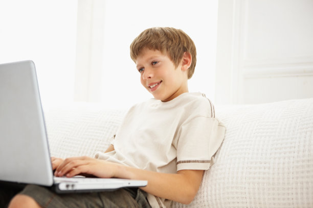 坐在沙发上用笔记本电脑的男孩图片下载