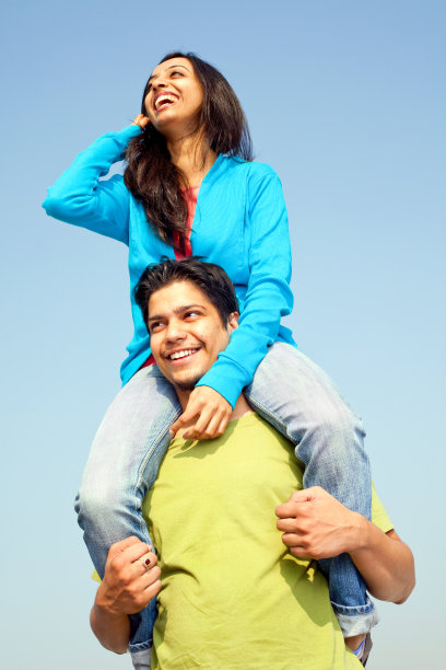 年轻开朗的印度男性成年人肩上背着女性朋友图片下载