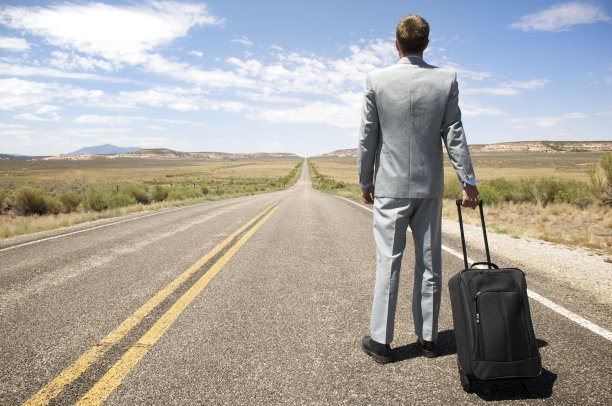 在孤独的高速公路上，一个商人拿着手提行李箱站在那里图片下载