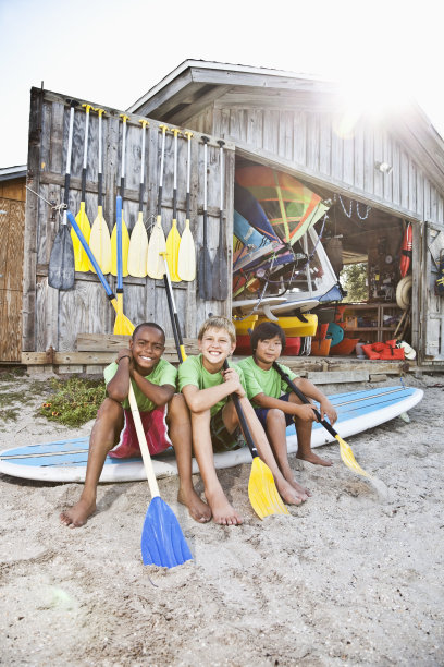 男孩子们在水上运动器材棚里划桨图片下载