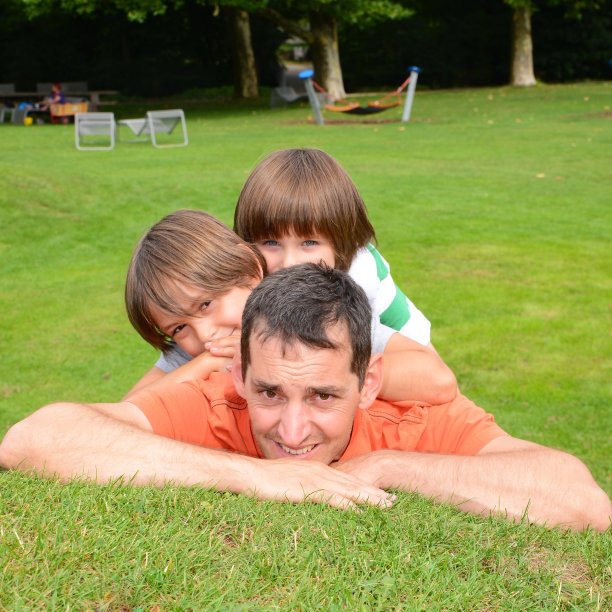 两个男孩爬在爸爸身上玩得很开心图片下载