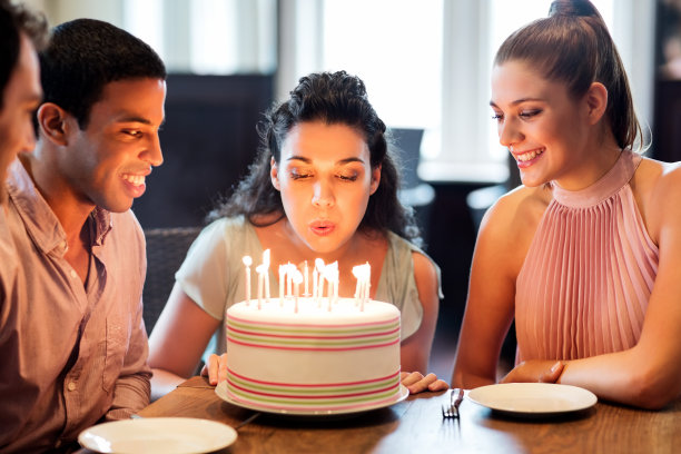 和朋友在蛋糕上吹蜡烛的女人图片下载