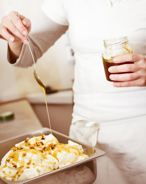女人把蜂蜜倒在香草和坚果冰淇淋上图片下载