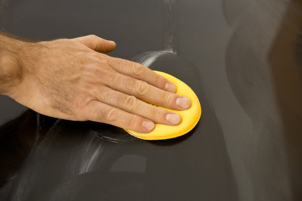 用黄色海绵擦拭一辆黑色汽车图片下载