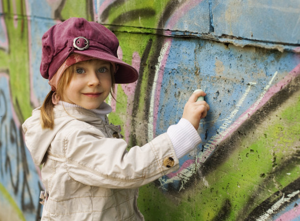 小女孩在涂鸦墙上用粉笔画画图片下载