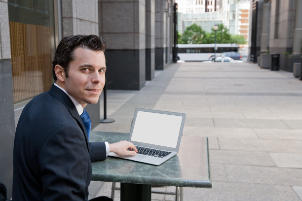 一个在户外公共场合拿着笔记本电脑的商人图片下载