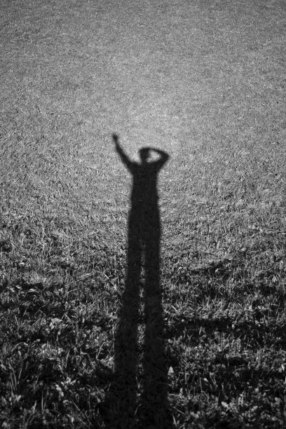 草地上一个挥舞着手的人的影子-单色图片下载