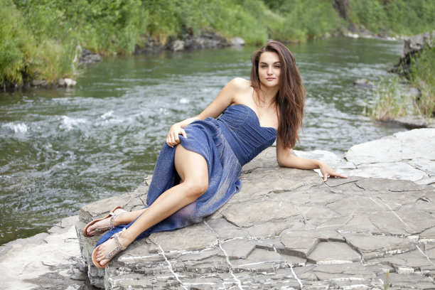 年轻的黑发女子躺在岩石上的时尚肖像。图片下载