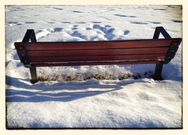 雪地里一条深褐色的公园长椅图片下载