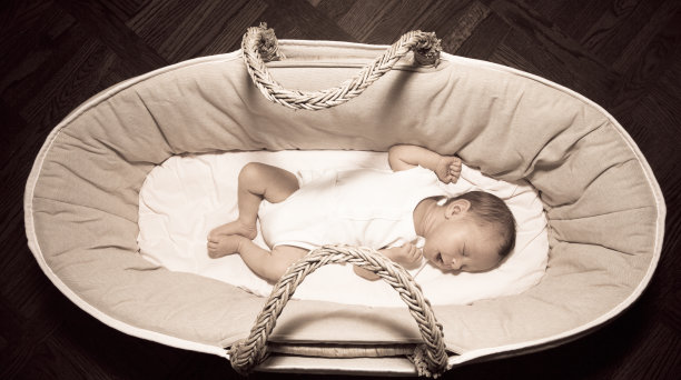 新生婴儿在摩西篮子里微笑着睡觉图片下载