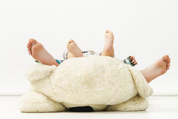 孩子们光着脚，妹妹和弟弟玩着泰迪熊图片下载