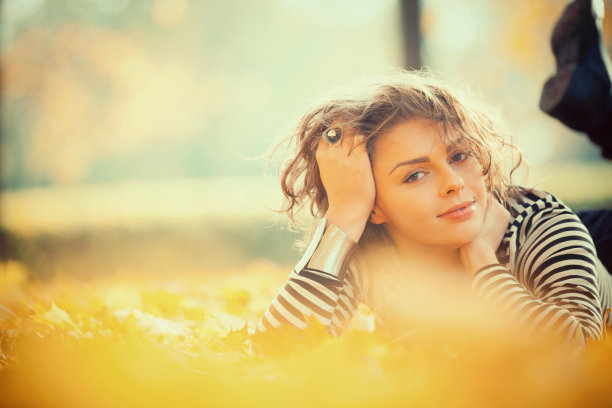 美丽的女人带着秋叶微笑着图片下载