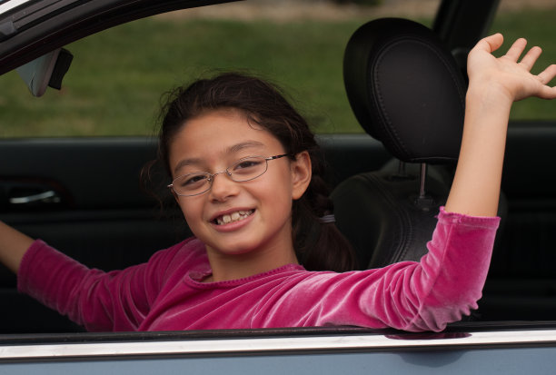 年轻女孩在驾驶座上挥手假装开车图片下载