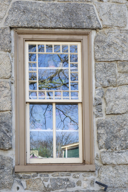 一个古老的石头房子的窗户上的倒影，垂直图片下载