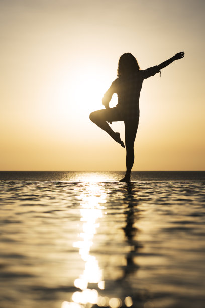 一个女人在泳池边做平衡练习的剪影。图片下载