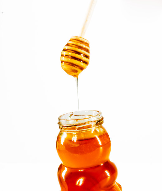 蜂蜜滴入瓶中孤立的白色图片下载