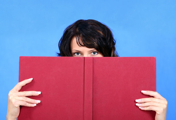 美丽的女人藏在一本书后面图片下载