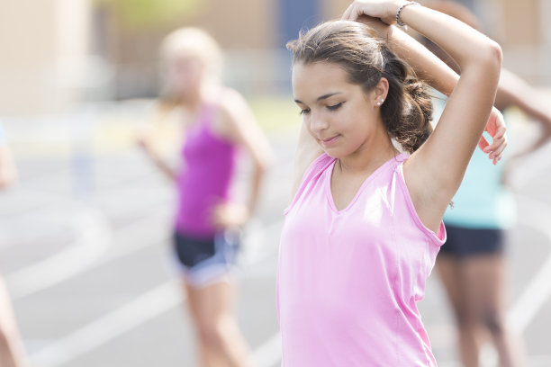 十几岁的女孩在跑道上跑步后伸展身体图片下载