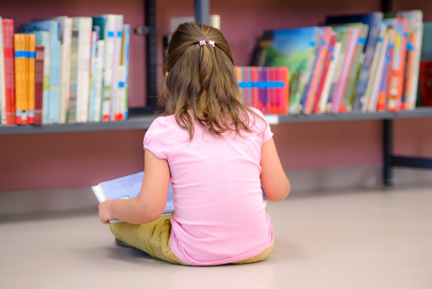 可爱的小女孩在图书馆的地板上图片下载