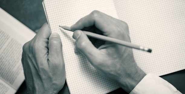 特写:男性用铅笔在笔记本上写字图片下载