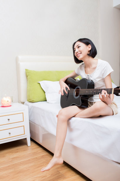 卧室里弹吉他的女孩的肖像图片下载