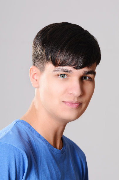 开朗英俊的少年在灰色孤立的背景蓝色t恤图片下载