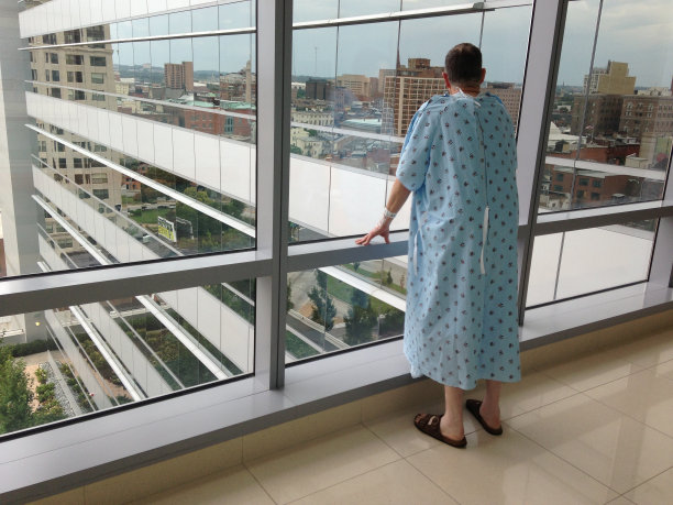 老年男病人向窗外看城市风景图片下载