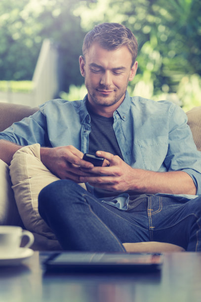 一个年轻人在用手机发短信。图片下载