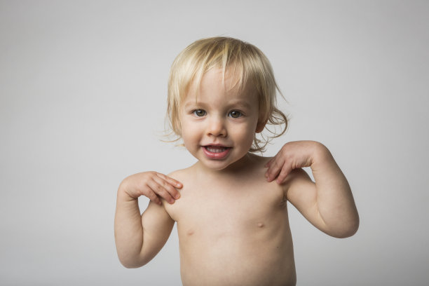 两岁赤裸上身的小男孩看着相机摸着肩膀图片下载