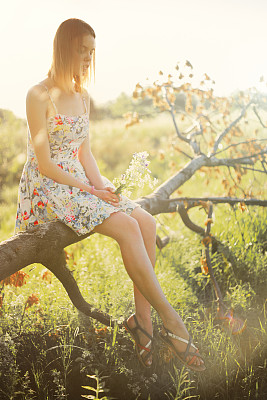 穿着衣服的年轻女子坐在树上图片下载