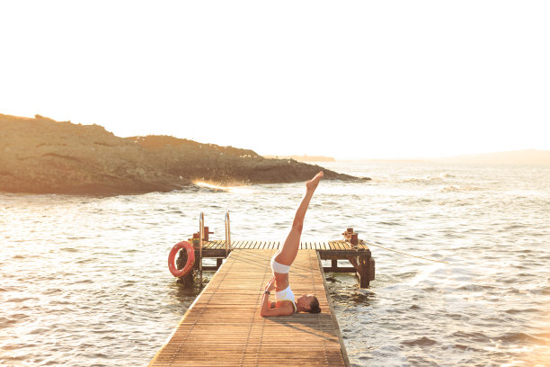 日落时分，年轻女子在码头上锻炼图片下载