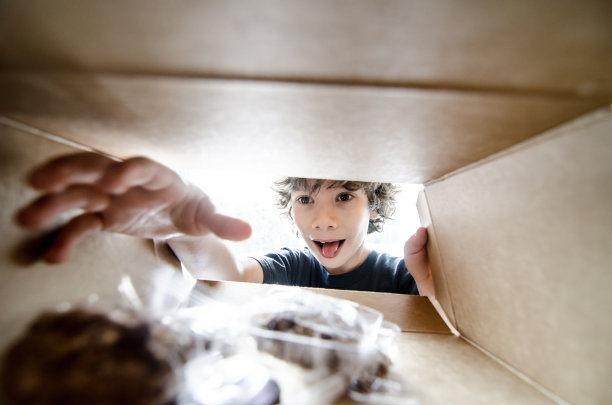 快乐男孩从里面拿了一个盒子里的饼干图片下载