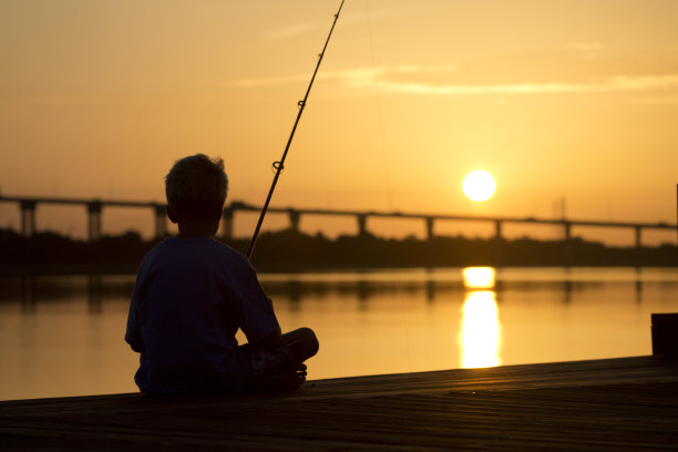 日出或日落，码头上的男孩在钓鱼图片下载