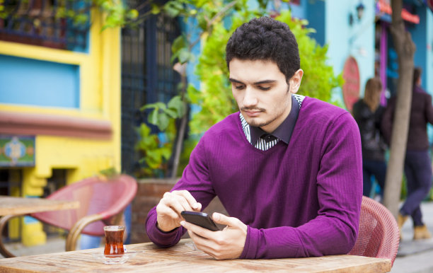 一名忧心忡忡的年轻人在咖啡馆用智能手机看短信图片下载
