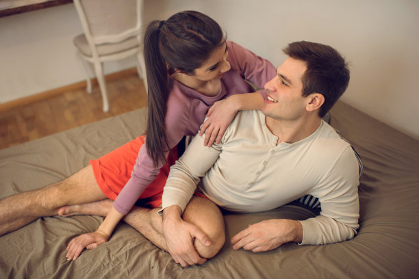 一对年轻相爱的夫妇在床上看着对方。图片下载