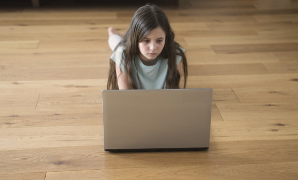 孩子躺在地板上玩电脑图片下载