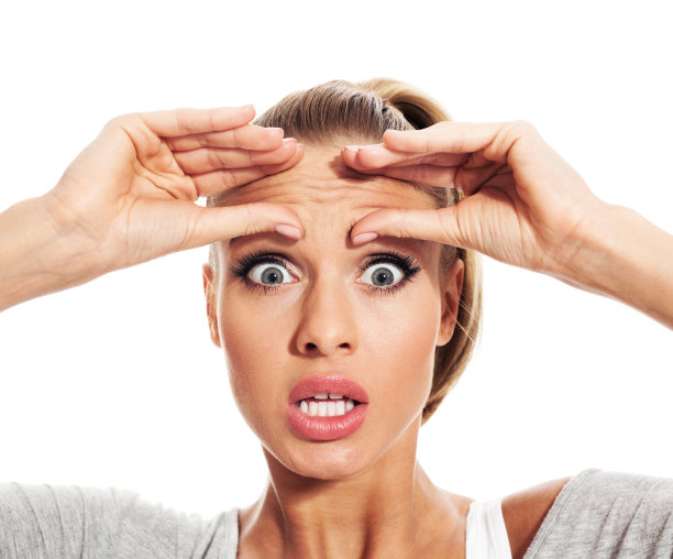 震惊的年轻女子检查她的皱纹图片下载