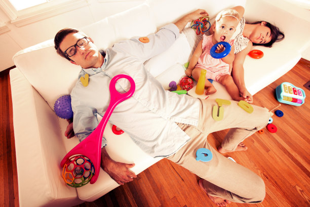 小女孩和她的父母在凌乱的床上图片下载