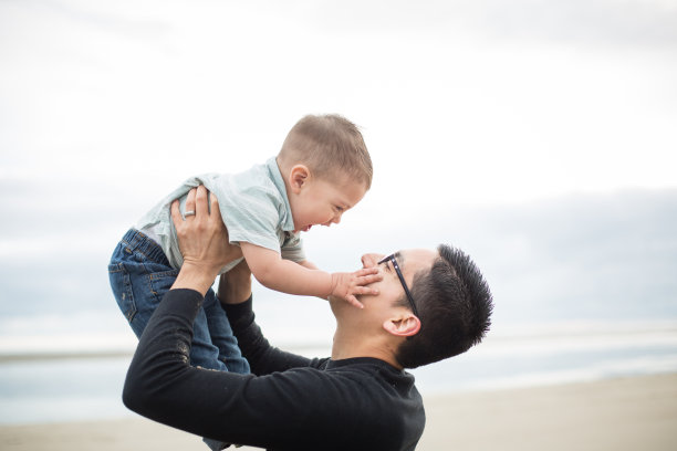 年轻的民族父亲和他的儿子在海滩上玩图片下载