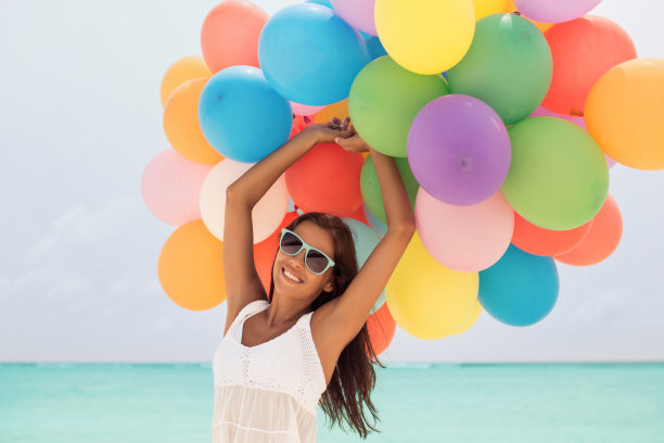 海滩上拿着气球的漂亮女孩图片下载