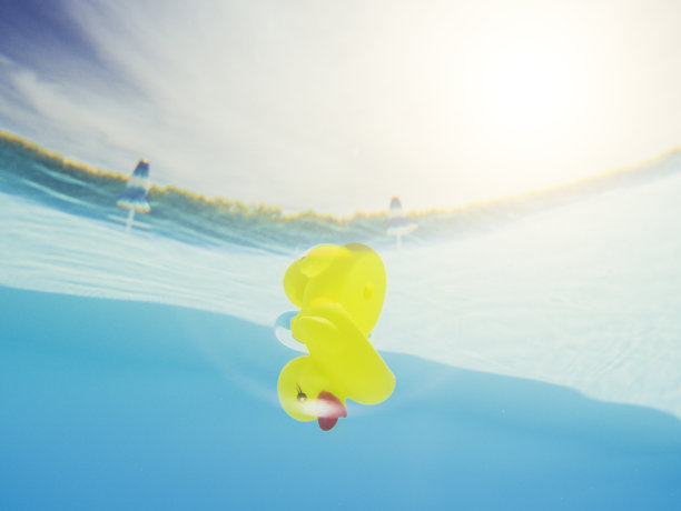 黄色的橡皮鸭在游泳池的水下漂浮图片下载