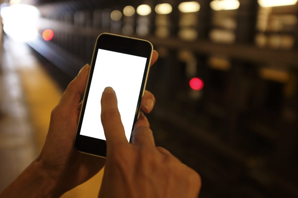 一个女人在地铁站里用智能手机图片下载