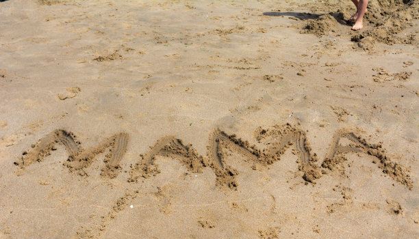 妈妈在沙滩上用孩子的手刮着字图片下载