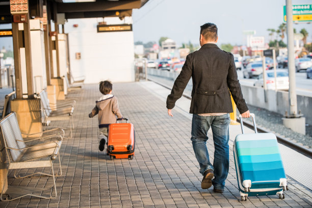 亚洲父子在火车站拉行李箱图片下载