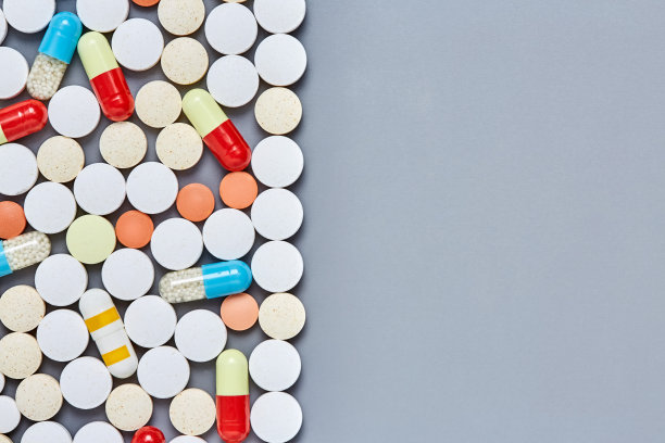 在灰色的背景上放置平铺的药片和胶囊素材图片