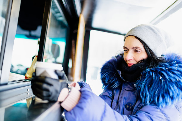 在路边咖啡馆里，一个女人拿着塑料杯喝着咖啡图片下载